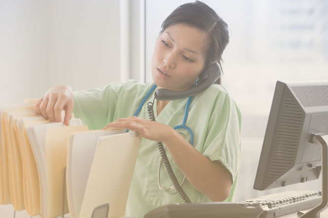 Person sorting through files protected by HIPAA cloud compliance while talking on phone.