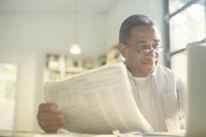 Enabled by a desktop app, a man enjoys reading a paper while working from home