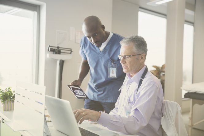 A male physician and male nurse discuss healthcare marketing solutions