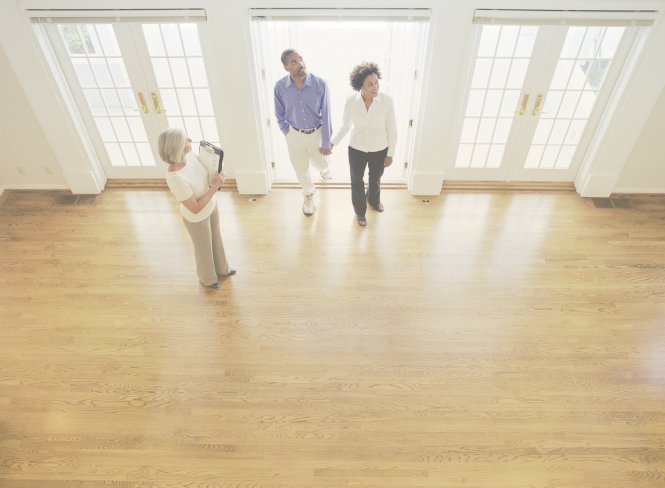A realtor shows a property to a man and a woman first reached via a real estate phone system