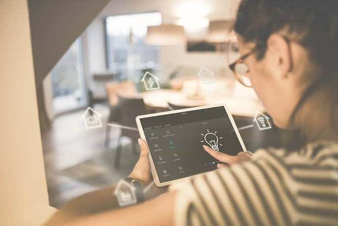 A woman seated at home with a tablet using smart home insurance technology trends