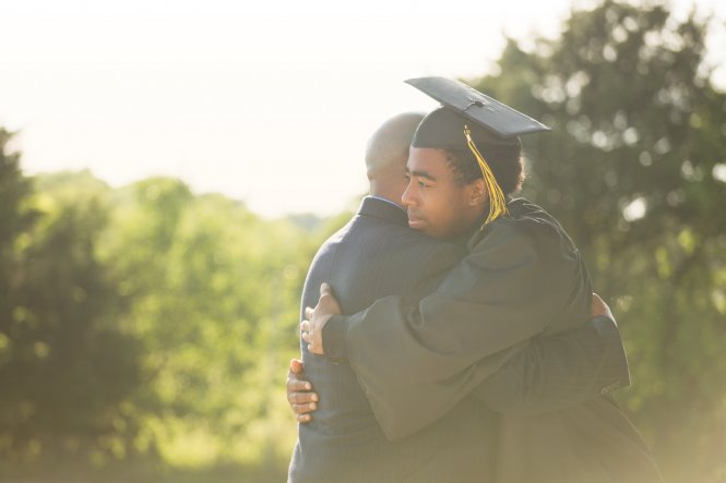 A young man who had an academic career enriched by mobile apps embraces his dad at graduation.