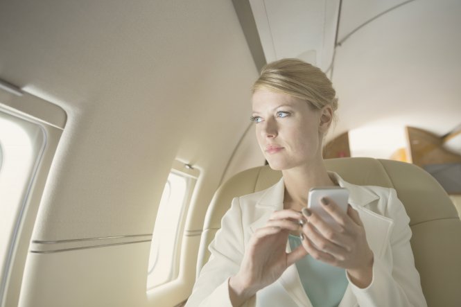 Traveler on a plane using the airline's API integration on her phone