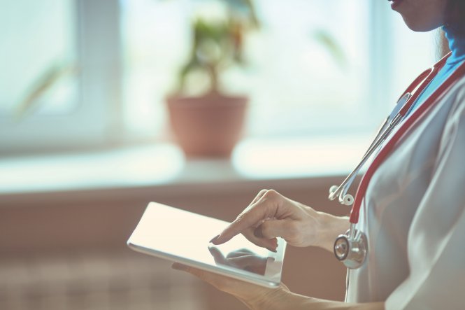 Doctor using HIPAA-compliant communication to talk with colleague via tablet