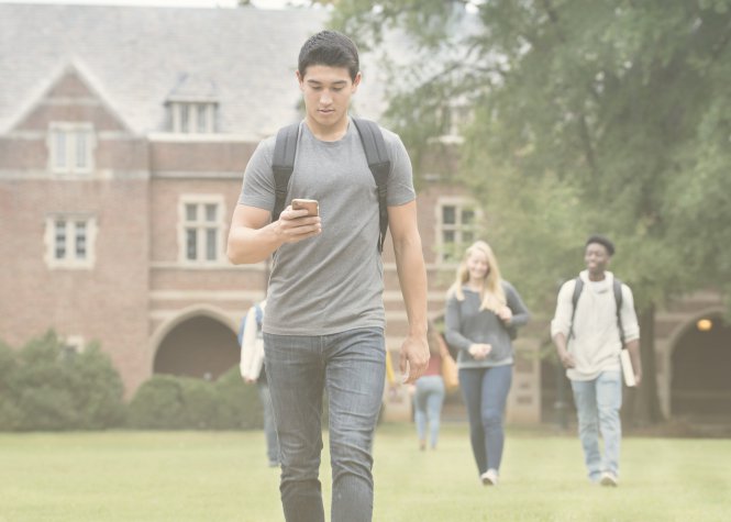 Student using flipped learning on smartphone and walking across campus with backpack on