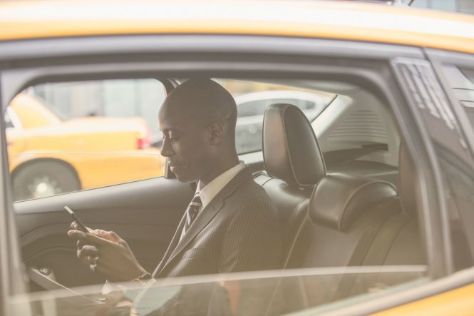 Person using mobile device in a taxi to access business files — UCaaS vs. VoIP