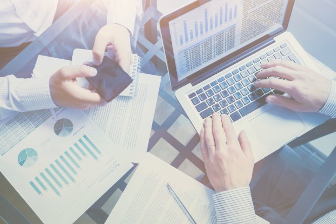 Two businesspeople working on a laptop and a smartphone using unified communications for business
