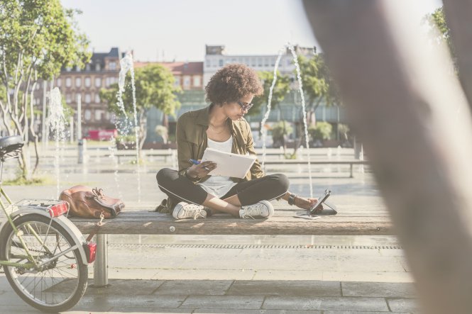 Person using 5G technology to work on tablet outside by a fountain