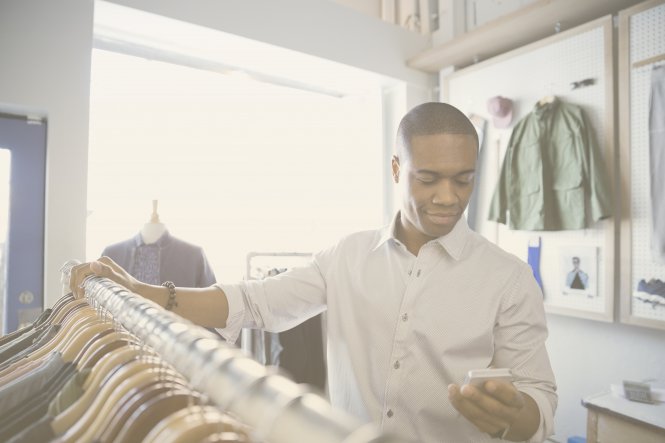 Person shopping in clothing store and looking at smartphone — UC customer experience integration