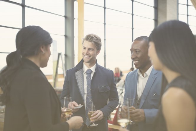 Four people sipping wine and smiling at each other — goals and objectives of IT department