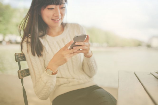 Person sitting in chair using smartphone and smiling — what are communications APIs