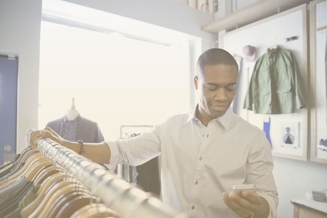 Business owner in a clothing store using SD-WAN solutions for retail organization via a smartphone