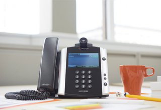 <p> An office telephone on a desk next to a cup of coffee.</p>