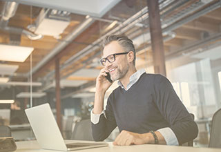 Person in office working on laptop and talking on smartphone — SIP definition