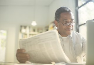 Enabled by a desktop app, a man enjoys reading a paper while working from home
