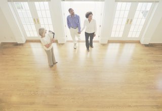 A realtor shows a property to a man and a woman first reached via a real estate phone system