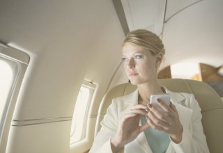 Traveler on a plane using the airline's API integration on her phone