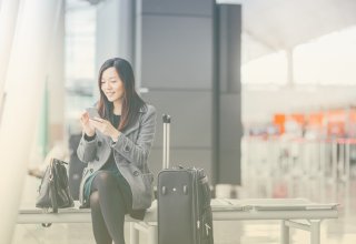 Traveling person in airport communicating with airline via travel itinerary API on smartphone