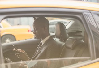 Person using mobile device in a taxi to access business files — UCaaS vs. VoIP