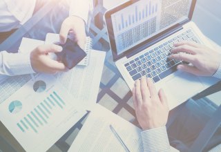Two businesspeople working on a laptop and a smartphone using unified communications for business