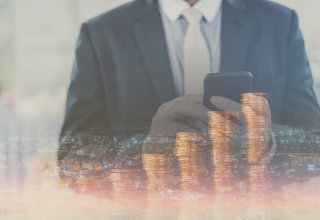 Person on smartphone in front of increasing coin stacks representing benefit of sales productivity