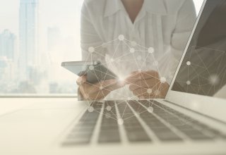 Person holding smartphone in front of a laptop and embracing the benefits of SIP trunking