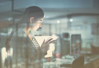 Person in office using tablet and standing in front of desks with computers — cloud migration