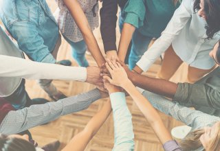 Team of people putting their hands together to collaborate — UCaaS integration