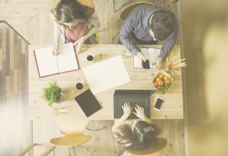 Three employees sitting at table working with smartphone, laptop, and paper — communication audit