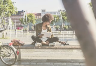 Person using 5G technology to work on tablet outside by a fountain