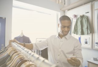 Person shopping in clothing store and looking at smartphone — UC customer experience integration