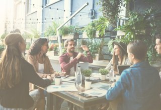 Group of employees sitting around table with computers and papers discussing UCaaS solutions