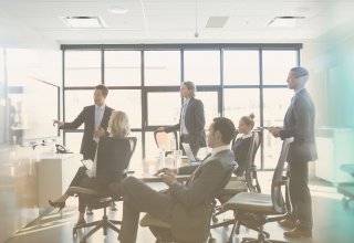 Group of businesspeople in suits looking at screen and discussing building client relationships