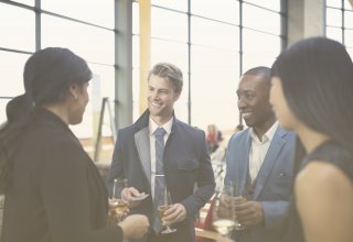 Four people sipping wine and smiling at each other — goals and objectives of IT department