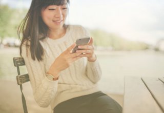 Person sitting in chair using smartphone and smiling — what are communications APIs