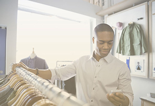 Business owner in a clothing store using SD-WAN solutions for retail organization via a smartphone